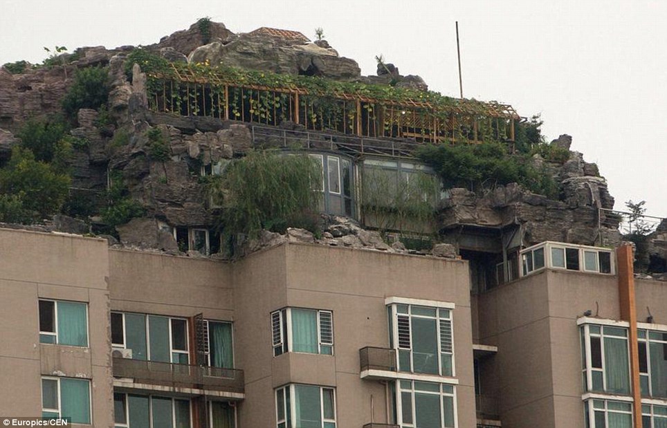 صيني يبني هضبة صخرية وفوقها فيلا على سطح عمارة